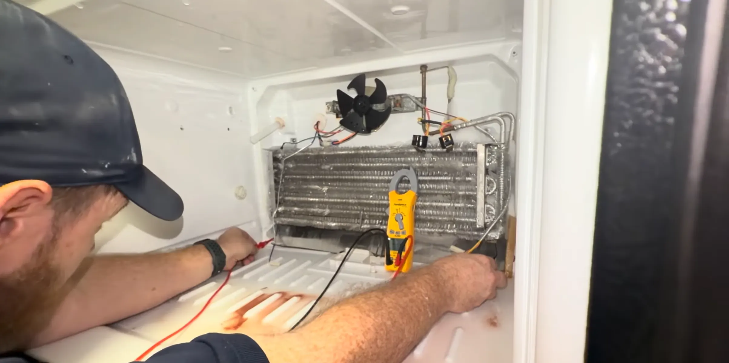 Technician testing a refrigerator evaporator and defrost heater with a meter during diagnosis