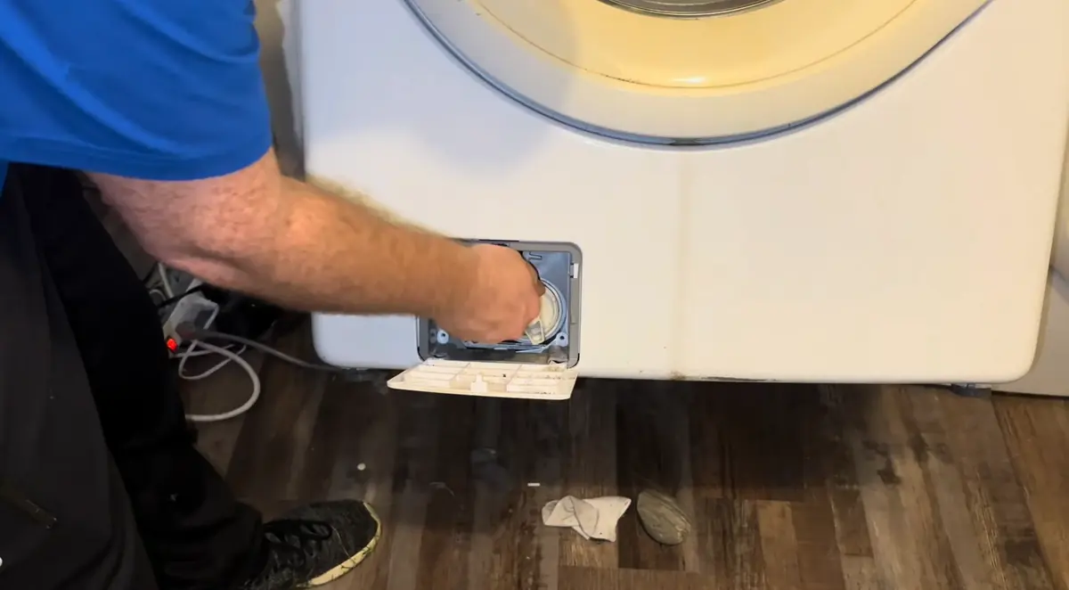 Technician opening the drain pump filter on a front load washer that will not drain